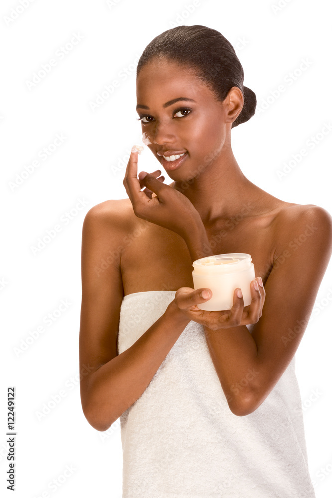 Afro-American girl wrapped in towel putting cream on face Afro-American girl wrapped in towel putting cream on face