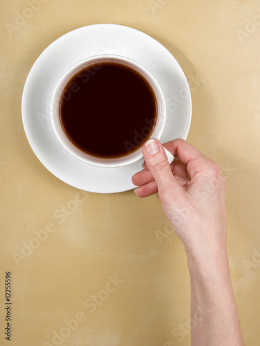 coffee - top view female hand holds a cup of tea on wood table -