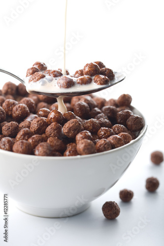 milk pouring into bowl with chocolate balls isolated