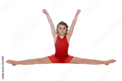 young girl doing a split with arms raised above her head