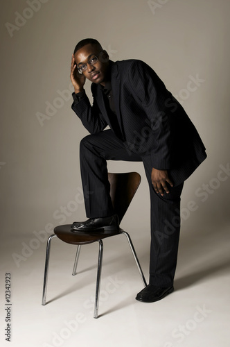 black male in suit with foot on a chair