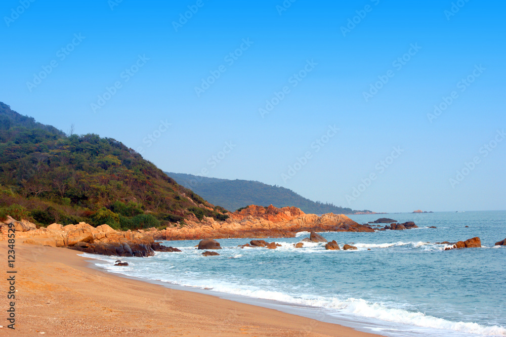 Obraz premium Lonely wild beach, high blue sky, cliff and coastline, tropical