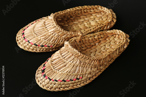 Bast shoes weaved of straw on a black background