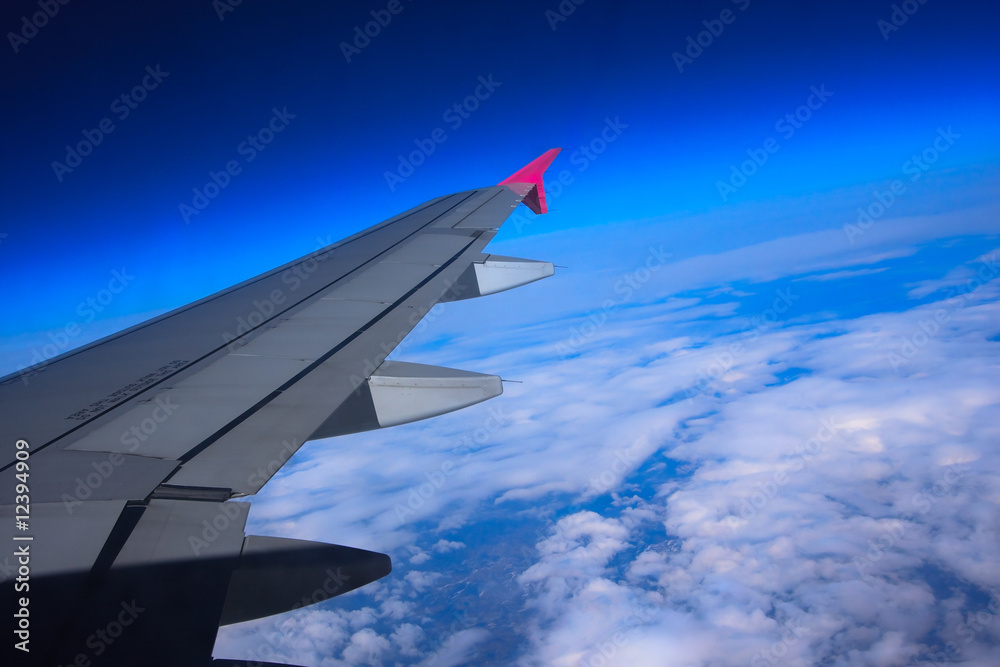 Fototapeta premium Aircraft wing flying high above the clouds