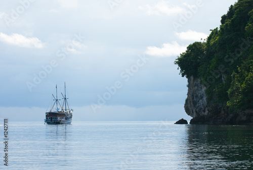 Yacht sailing next to rocky island