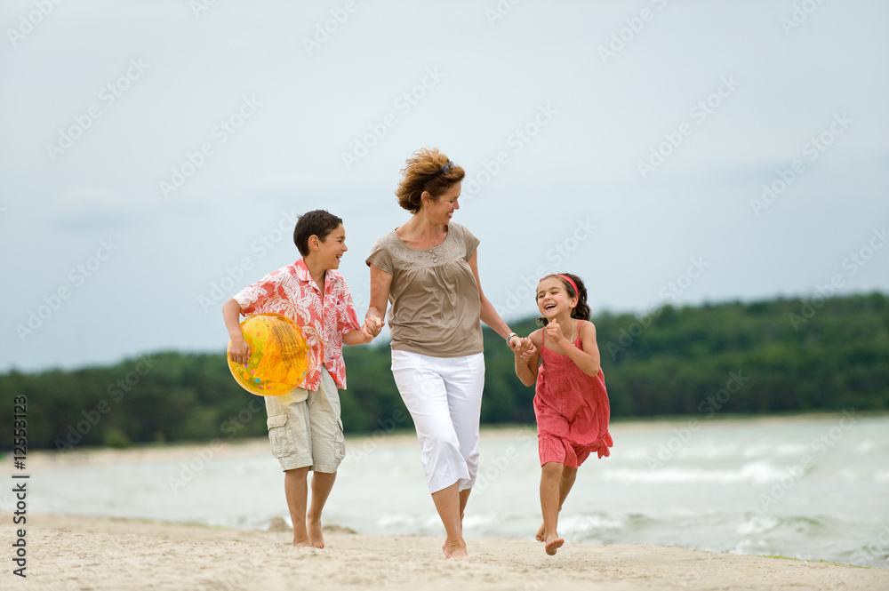 Happy mother and kids walking on the beach