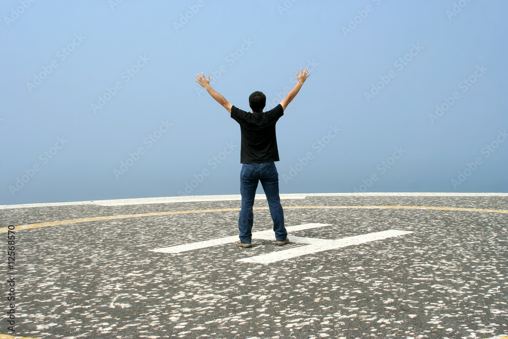 young man with arms open contemplating the ocean young man with arms open contemplating the ocean