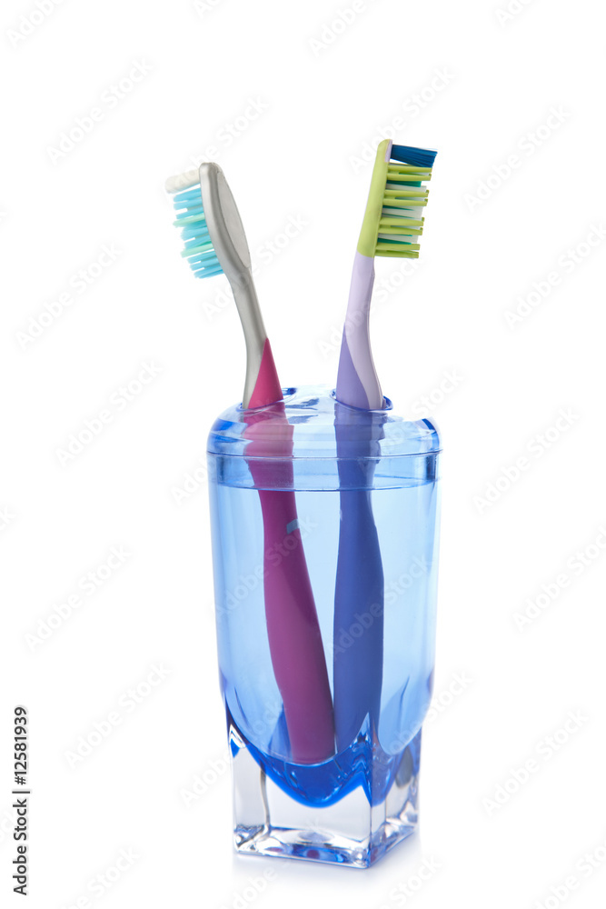 two colorful toothbrushes in glass isolated two colorful toothbrushes in glass isolated
