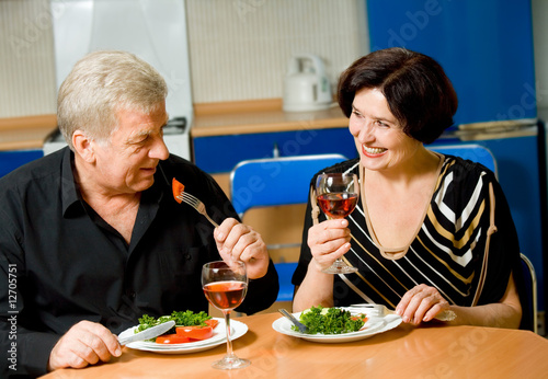 Elderly happy smiling couple eating together at home