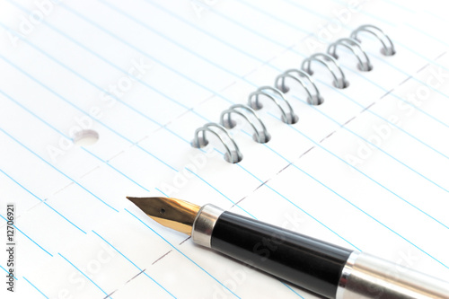 A gold nibbed pen on a spiral-bound notepad