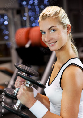 Strong beautiful woman lifting heavy dumbbells