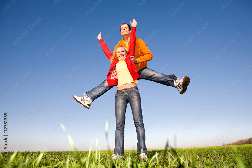 Happy smiling couple jumping in blue sky Happy smiling couple jumping in blue sky