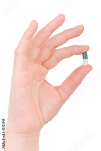 Hand holding a capsule or pill isolated on white