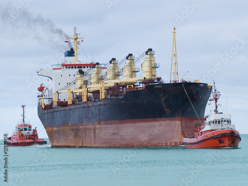 Two tugboats assisting huge vessel