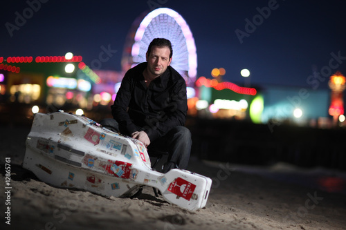 Musician with travel cello or guitar case on beach at night photo