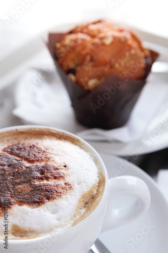 coffee cappuccino with dusting cocoa and muffin on background