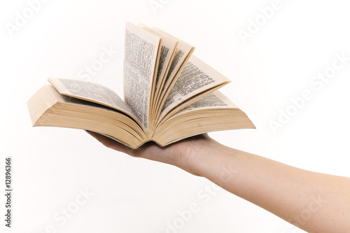 The hand holds the book on a white background