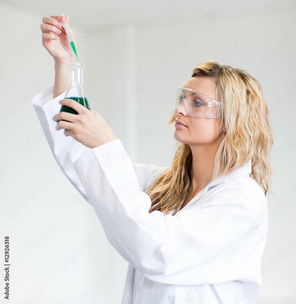 Woman in lapcoat looking at chemicals Woman in lapcoat looking at chemicals