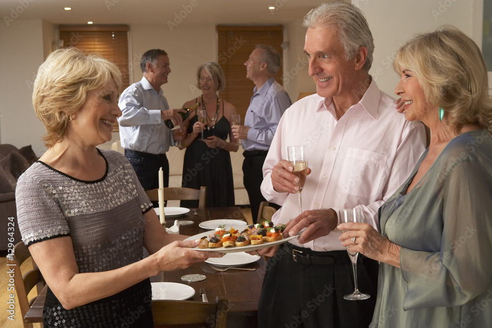 Woman Serving Hors D'oeuvres To Her Guests At A Dinner Party