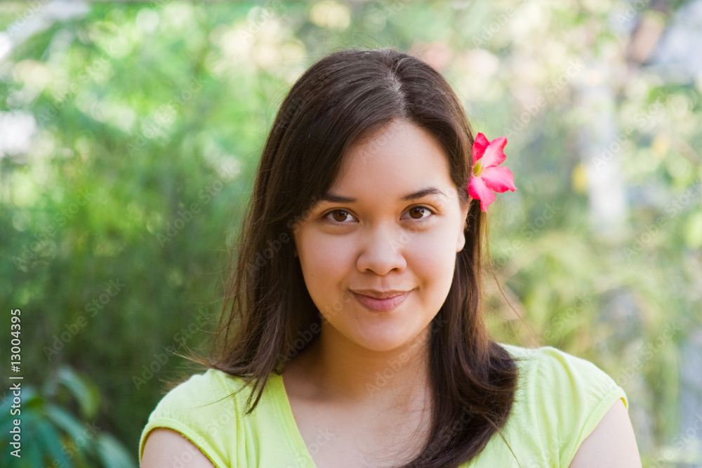 Φωτογραφία Smiling woman with pink plumeria tucked behind ear
