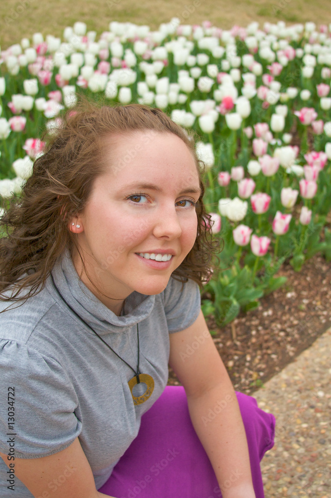 Fototapeta premium A pretty young girl poses in front of early spring flowers