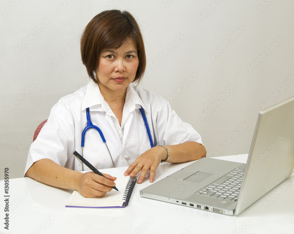 Asian Doctor sitting at her desk and writing Asian Doctor sitting at her desk and writing