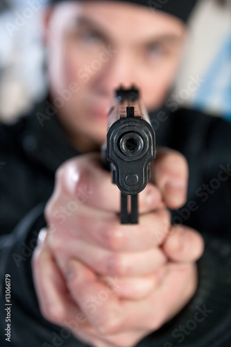 Young man pointing a gun straight at the camera