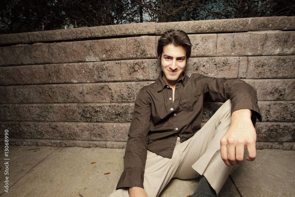 Man sitting by a wall and smiling Man sitting by a wall and smiling