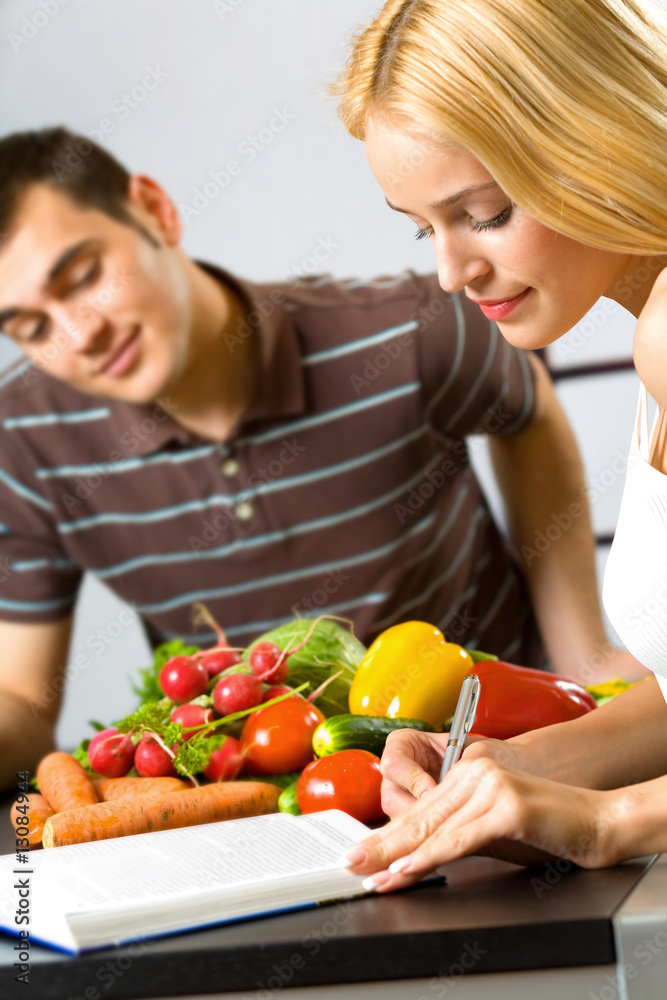 Young happy woman studing and man cooking at kitchen Young happy woman studing and man cooking at kitchen