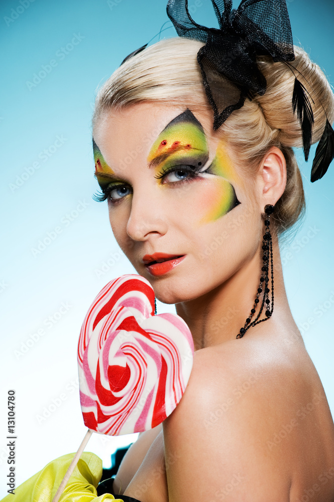 Young beauty with butterfly face-art heart shaped lollypop