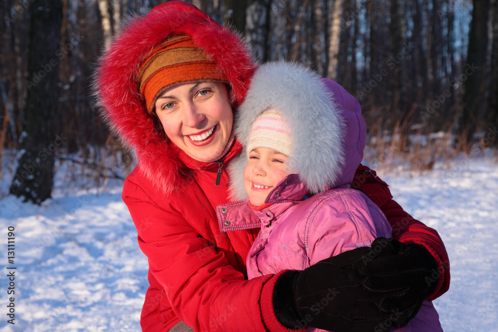 Mother embraces daughter in park in winter