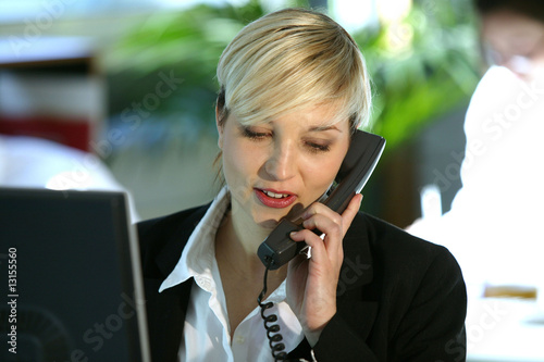 femme au téléphone devant un ordinateur de bureau photo