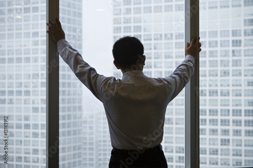 asian business executive looking through office window