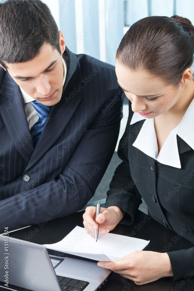 Two happy businesspeople signing document at office Two happy businesspeople signing document at office