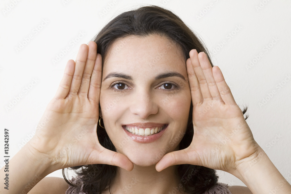 Fototapeta premium Young woman frame her face with palms