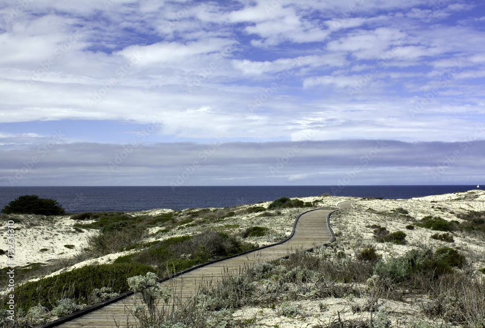 Boardwalk over sand dunes with blue sky and clouds on the Califo