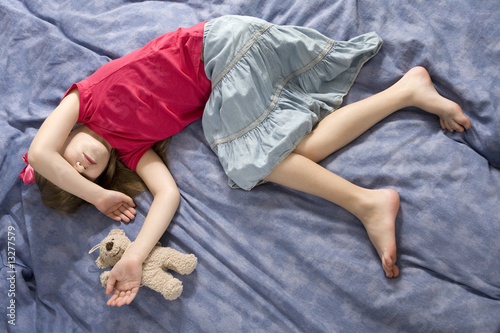 little sleeping girl in bow with teddy-bear