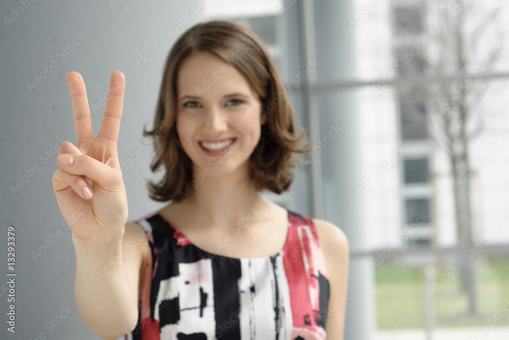 junge frau macht victory zeichen mit fingern und lacht junge frau macht victory zeichen mit fingern und lacht