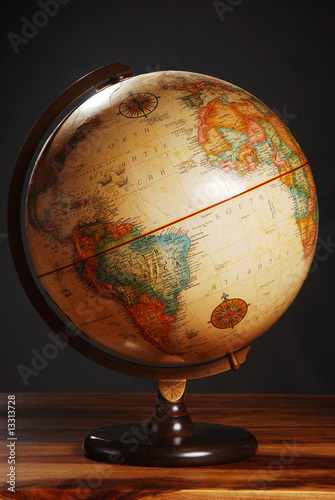 An antique globe on a table with a dark grey background