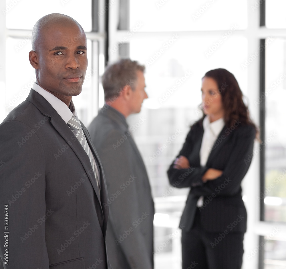 Serious business leader looking at camera in front of team Serious business leader looking at camera in front of team