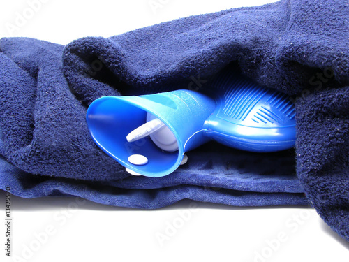 Blaue Wärmflasche eingehüllt in eine blaue Decke