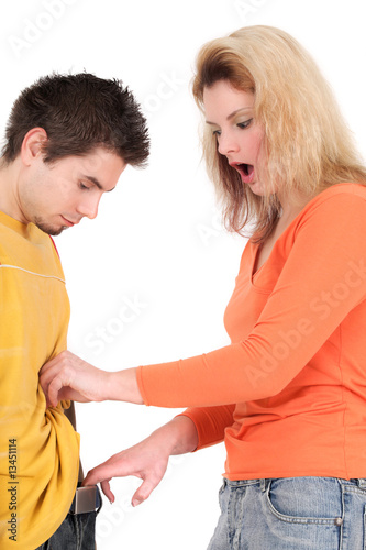 Portrait of young woman looking in man's pants with shocked expr