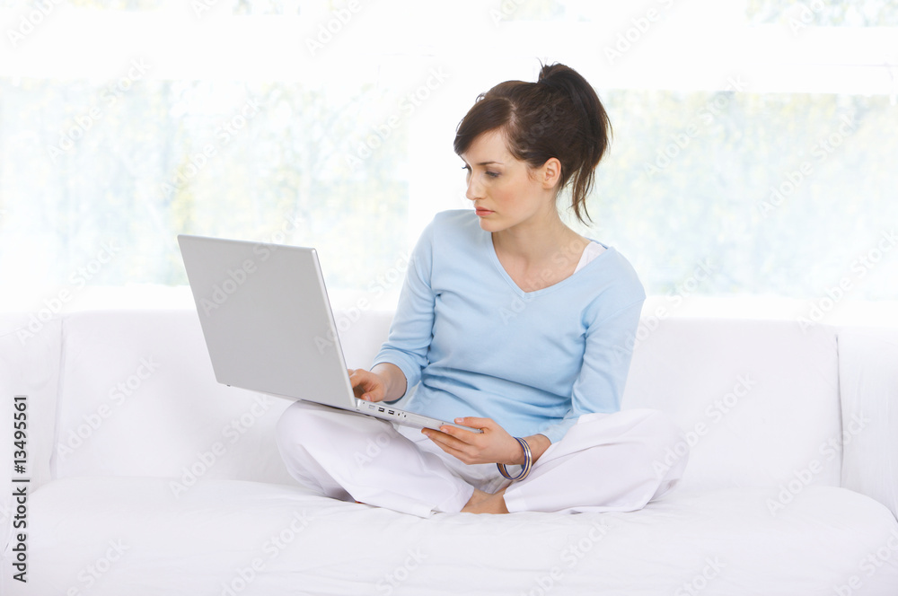 Young woman is on couch and working on laptop Young woman is on couch and working on laptop