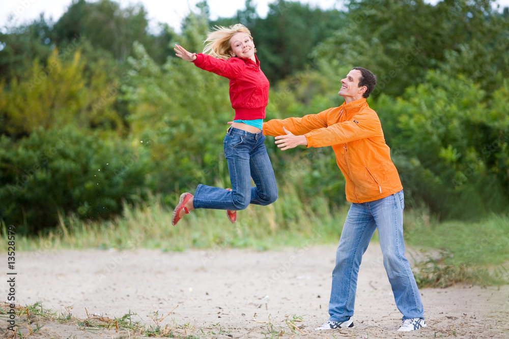 Fototapeta premium Happy Young Couple - jumping against a green tree
