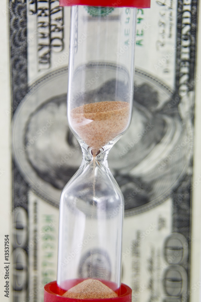 Closeup view of sand flowing through an hourglass on the backgro Closeup view of sand flowing through an hourglass on the backgro