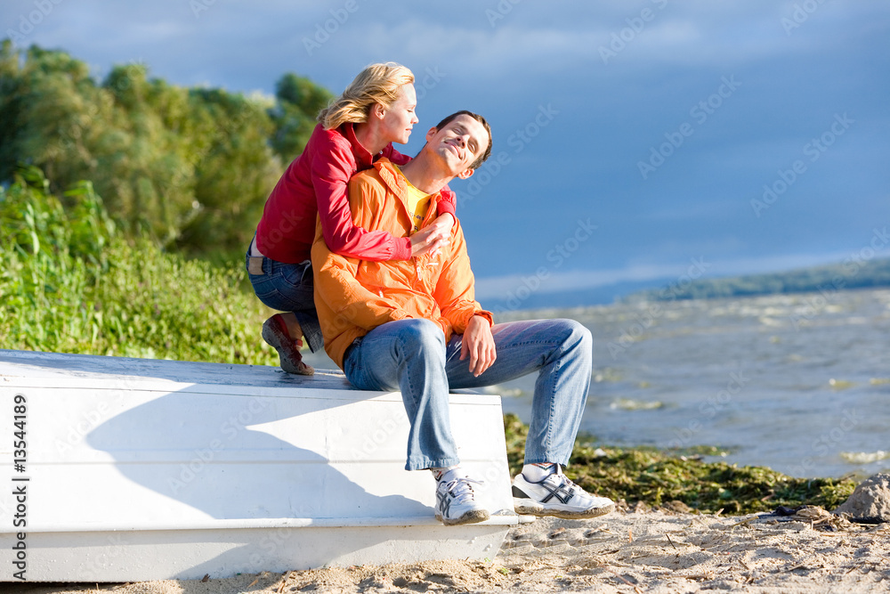 Young love Couple sit on boat on bank of river