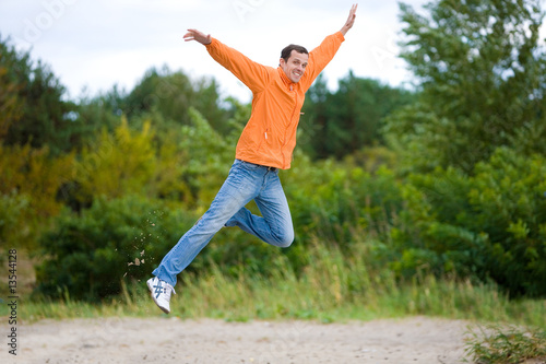 Happy Young Man - jumping in the sky against a green tree