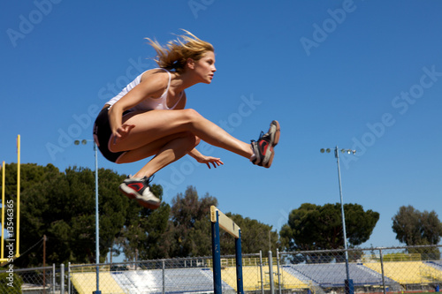 Athletic girl hurdling at the track