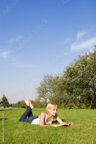 young blonde reads book in the park
