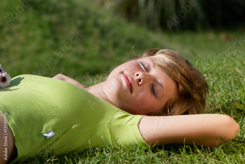 The young girl having a rest on a grass in park